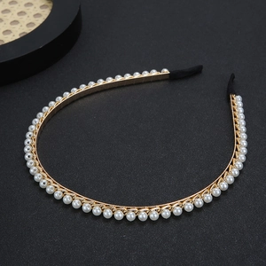Elegant gold metal thin headband with white pearls for women on black background