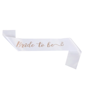Detailed view of white satin Bride to be sash with elegant champagne gold foil lettering