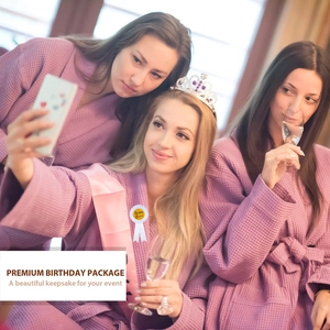 Trois amies en peignoirs violets fêtant avec écharpe et couronne de Birthday Queen et badge