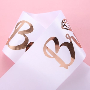 Close-up of white satin bridal sash with rose gold Bride lettering and diamond icon