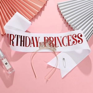 Close-up of Birthday Princess sash and rhinestone crown set on festive pink background
