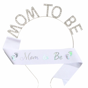 Détail du serre-tête Mom To Be en strass et écharpe en satin blanc avec pieds de bébé