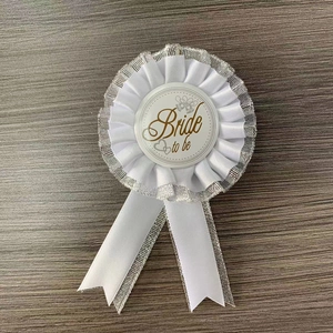 Detailed view of a white lace Bride to Be wedding badge with gold glitter accents
