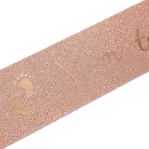 Gros plan sur une écharpe Mom to be or rose pailletée avec empreintes pour baby shower