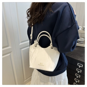 Detail of white pleated leather bucket bag with gold logo and adjustable shoulder strap