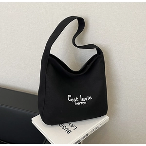 Minimalist black canvas tote bag with white C'est lavie script on stylish magazine