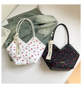 Détail de sacs seaux tendance à imprimé cerise avec sangles contrastées et étiquette