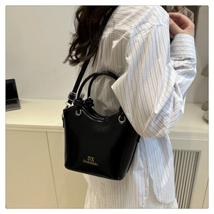 Detail of a black glossy bucket bag showing premium leather texture and golden logo