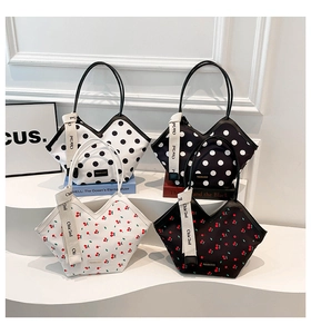 Détails de quatre sacs cabas à motifs cerises et pois exposés sur des présentoirs