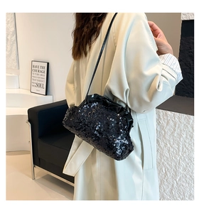 Close-up of a black sequin pleated evening clutch with a slim leather shoulder strap