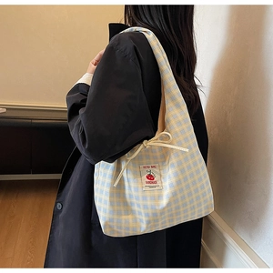 Dettaglio della borsa tote in tela a scacchi gialli e blu con etichetta e coulisse