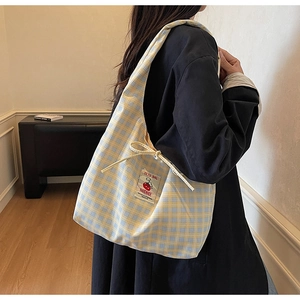 Detail of yellow and blue plaid canvas tote bag with cherry logo and handmade label