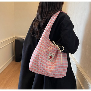 Dettaglio della borsa tote in tela a quadretti rosa con patch e fiocco decorativo