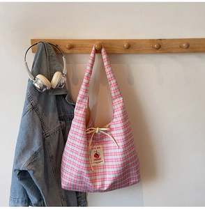 Detail of pink plaid tote bag with handmade textile label and yellow rope handle closure