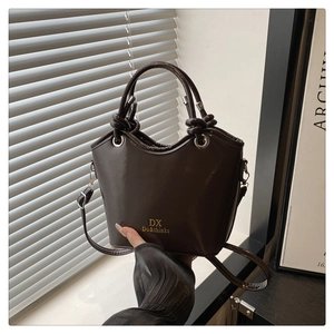 Detail showing chocolate brown glossy faux leather bucket bag with knotted handle detail