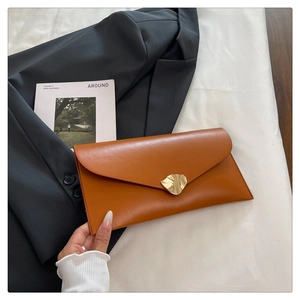 Gros plan de la pochette marron caramel avec boucle dorée de forme organique unique