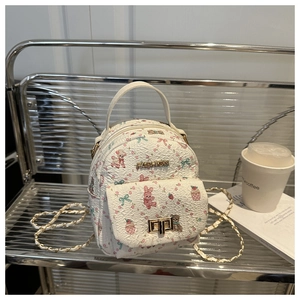 Detailed close-up of a white floral printed mini backpack on a modern metal chair