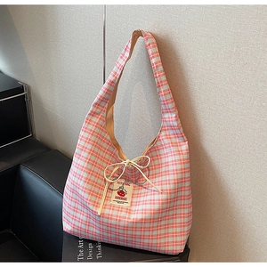 Detail of red gingham canvas tote bag featuring bow tie closure and tomato woven label