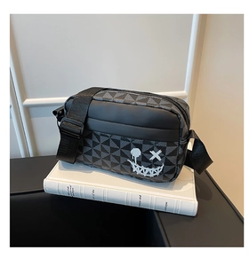 Detail of checkered crossbody bag with graffiti smiley face embroidery and adjustable strap
