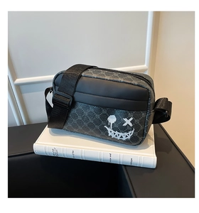 Close-up of stylish grey patterned crossbody bag featuring an embroidered smiley face