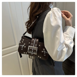 Detail of dark chocolate vintage biker bag with silver rivets and metal buckle hardware