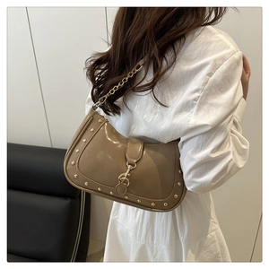 Detail view of khaki crescent bag with shiny texture and golden rivet studs