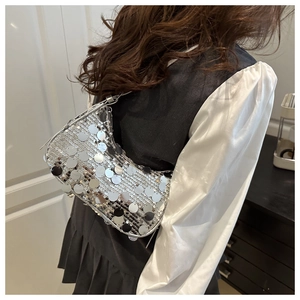 Close-up of a silver sequined crescent Hobo bag worn as an elegant underarm style