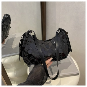 Detail of black sequined crescent bag showing sparkling circular textures and leather strap