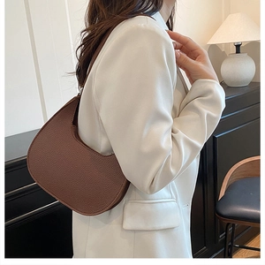 Detailed view of deep brown pebbled leather crescent bag styled with white blazer outfit
