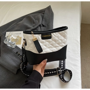 Detail of quilted monochrome shoulder bag with fashion label and adjustable wide strap