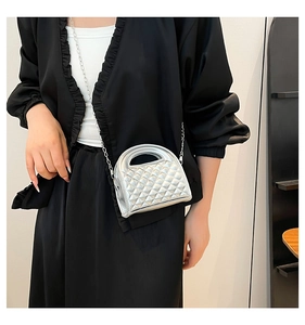 Detail view of silver quilted handbag with metallic finish and elegant chain strap on model