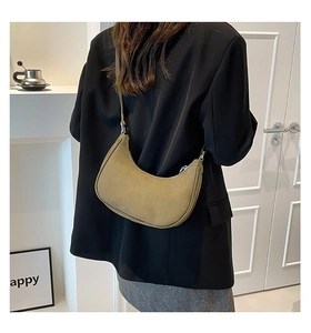 Olive green suede crescent moon bag worn with a black blazer in a minimalist setting
