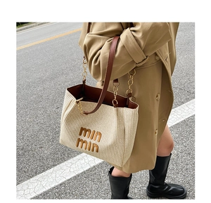 Dettaglio della borsa tote intrecciata beige con finiture in pelle e catena dorata