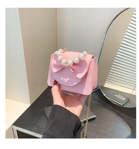 Close-up of pink mini bag with bow decoration and elegant pearl handle strap