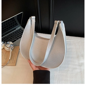 Detailed texture of silver lychee pattern crescent bag on office desk with lifestyle props