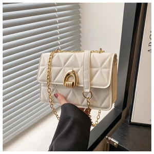 Détail d'un sac bandoulière blanc matelassé avec chaîne dorée et fermoir métallique