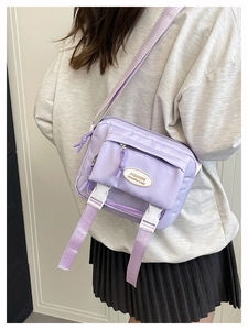 Dettaglio della borsa messenger viola chiaro con fibbie e tracolla regolabile sulla modella
