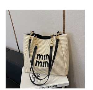 Dettaglio della borsa tote in tessuto con ricamo nero, tracolla in pelle e catena dorata