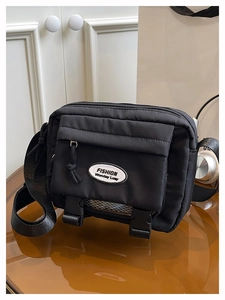 Detail of black nylon messenger bag with white oval patch and adjustable strap