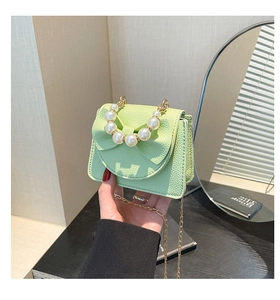 Detail of light green crossbody bag with pearl handle and leather bow decoration