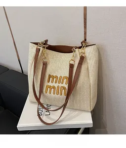 Dettaglio della borsa tote intrecciata beige con ricamo giallo e cinturino in pelle