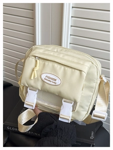 Detail view of cream yellow nylon messenger bag with white mesh pocket and plastic buckles
