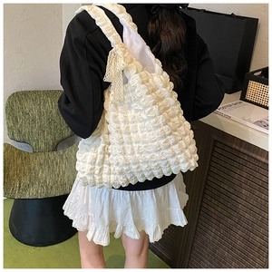 Detail of white bubble tote bag with lace bow decoration worn by a model on shoulder