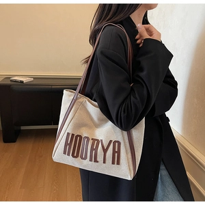 Detailed close-up of large canvas tote bag with brown leather handles and HOORYA branding