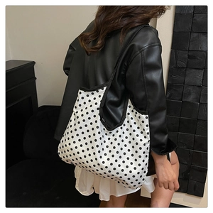 Vue de dos d'un mannequin portant un grand sac cabas à pois avec des anses noires