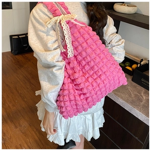 Detail of pink puckered texture bag with lace bow decoration worn by model in a room
