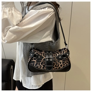 Close-up of leopard print fabric detail with silver rivets on a leather shoulder bag