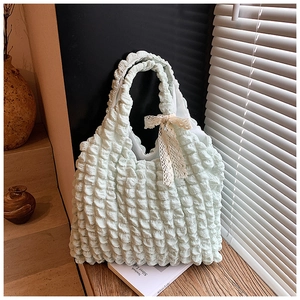 Detail of light green puff tote bag with bubble texture and a white lace bow accessory