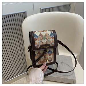 Detail of small crossbody bag with brown leather frame and colorful geometric woven fabric