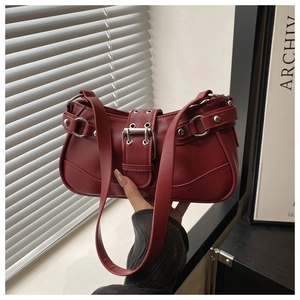 Macro detail of dark red leather shoulder bag with vintage buckles and metal eyelets